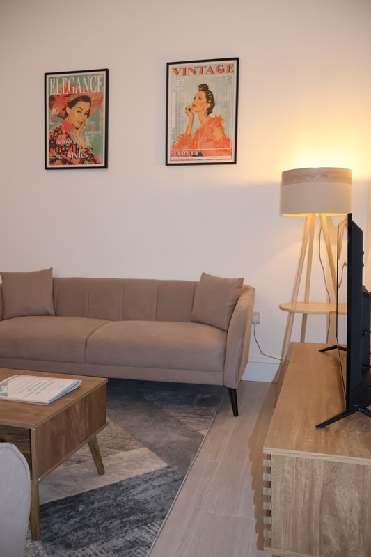 Living room with beige sofa, wooden coffee table, floor lamp, and vintage framed wall art