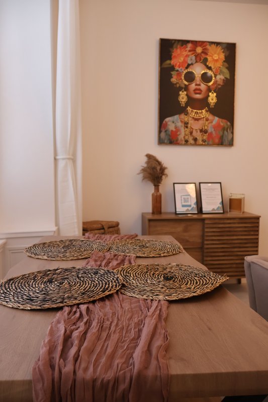 Bedroom with bed, decorative woven placemats, pink throw, wooden dresser and framed wall art