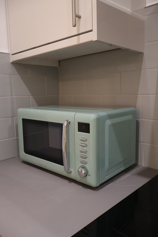 Kitchen counter with pale green microwave oven and white wall cabinets above