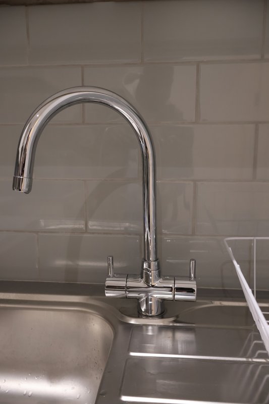 Modern kitchen sink with chrome tap and subway tile backsplash