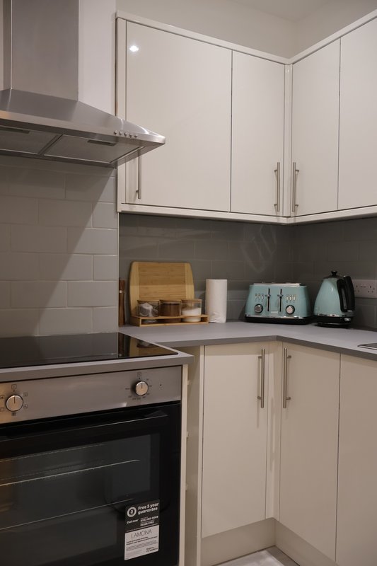 Modern kitchen with cream cabinets, black countertop, stainless steel range hood and built-in oven
