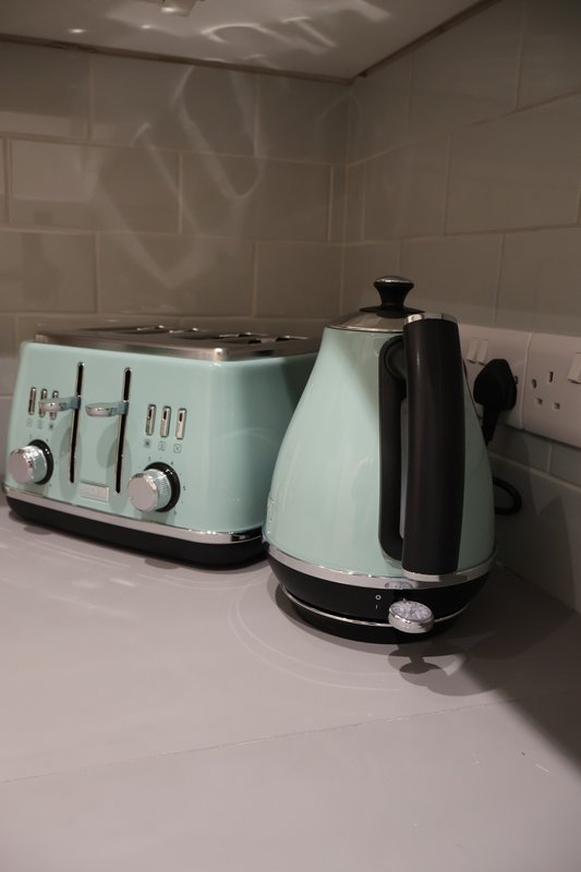 Modern kitchen counter with mint green toaster and kettle, white subway tile backsplash