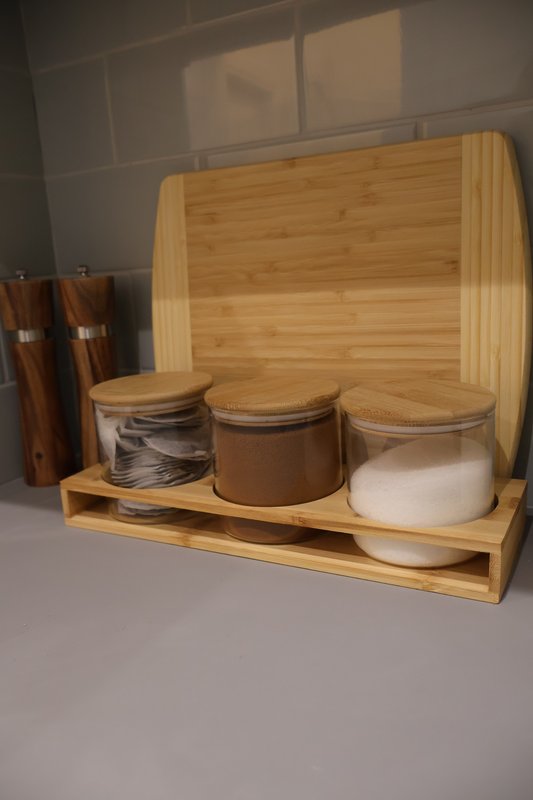 Wooden kitchen organizer with storage containers and cutting board on white counter