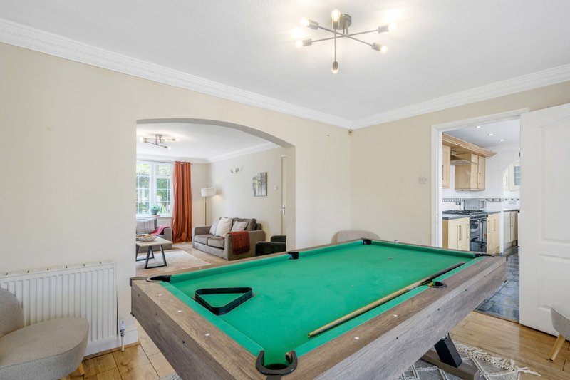 Recreation room with green pool table, doorway to living area, and kitchen visible beyond