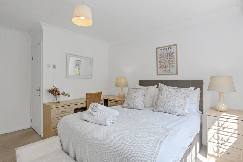 Bright bedroom with double bed, wooden bedside tables, white walls and ceiling lamp