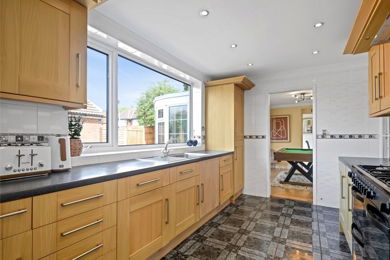 Modern kitchen with wooden cabinets, dark countertop, stainless steel range cooker and garden view