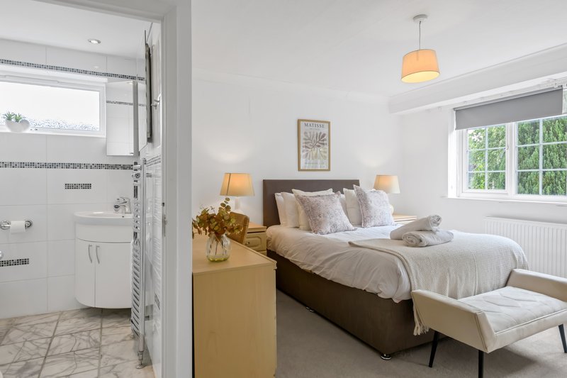 Bright bedroom with double bed, ensuite bathroom visible, pendant lamp and side tables