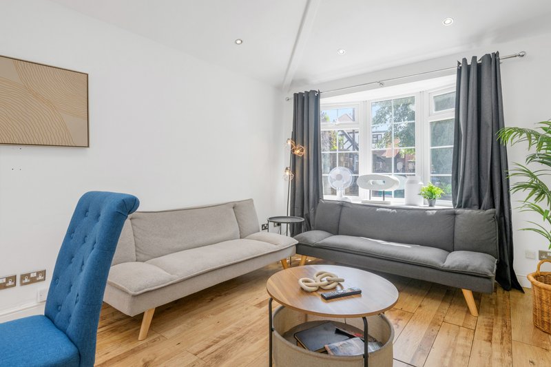 Modern living room with gray sectional sofa, blue armchair, wooden coffee table and large windows