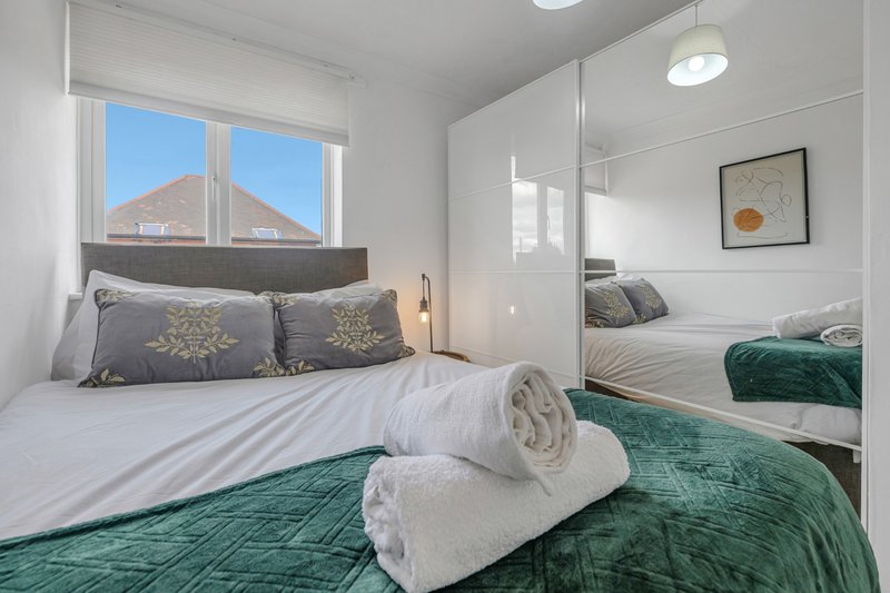 Modern bedroom with double bed, rolled towels, mirrored wardrobe and mountain view window