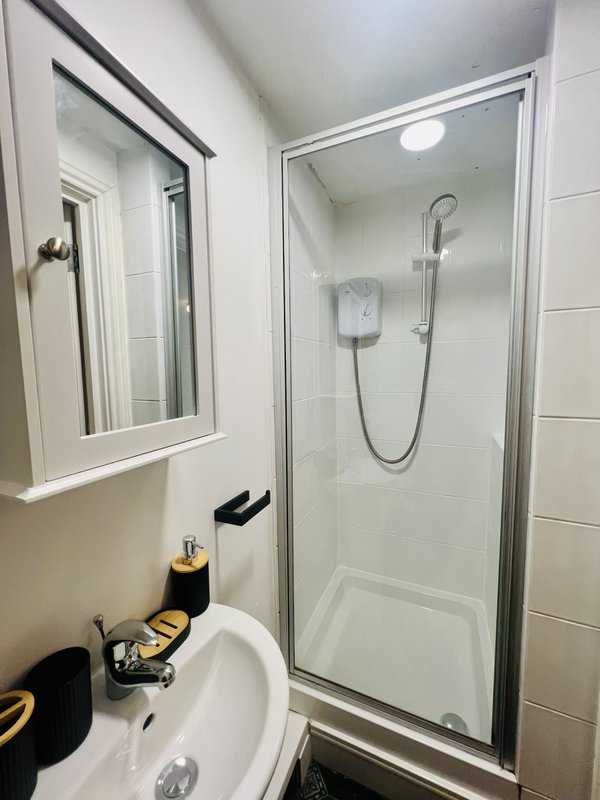 Modern bathroom with white sink, mirror, shower enclosure and tiled walls