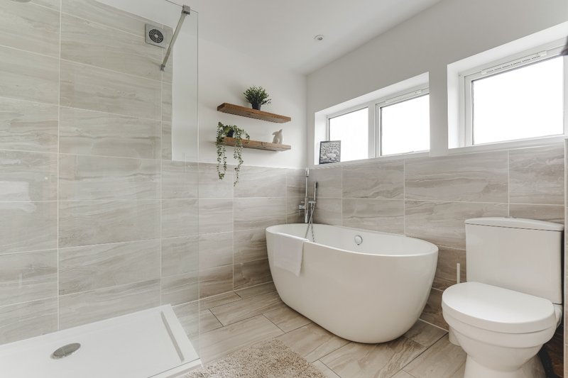 Modern bathroom with freestanding bathtub, walk-in shower, toilet, and floating shelves