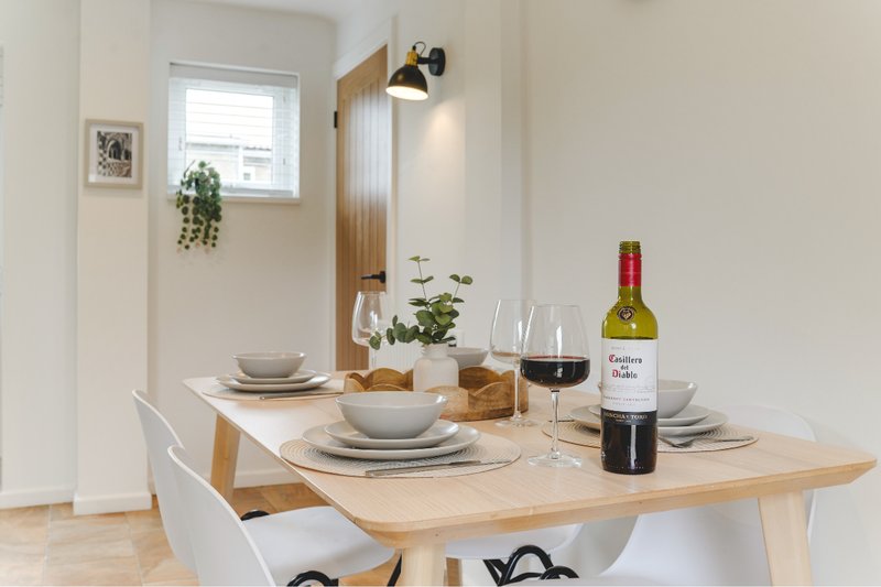 Minimalist dining table set for two with wine bottle, glasses, and place settings