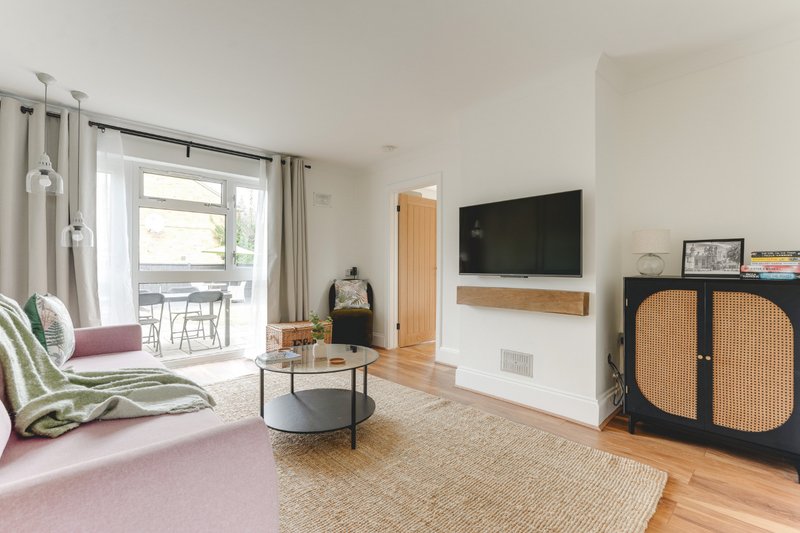 Bright open-plan living room with sofa, TV, wooden floor and patio doors