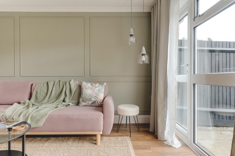 Light-filled living room with pink sofa, throws, pendant lights and large windows