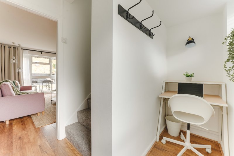 Modern home office nook with white desk chair, shelving unit, and wooden flooring
