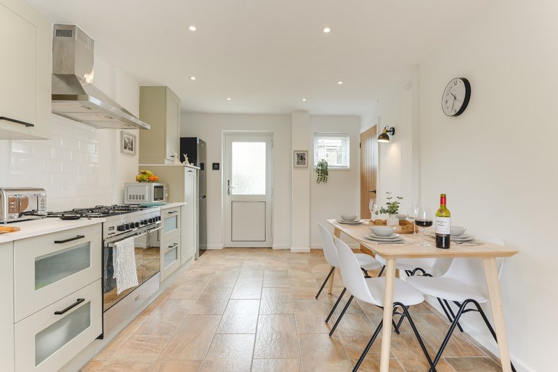Modern kitchen with white cabinetry, stainless steel appliances, dining table and chairs