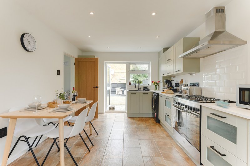 Modern kitchen with cream cabinetry, gas range, wooden dining table and chairs