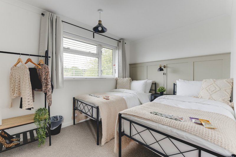 Bright bedroom with two single beds, black metal frames, white bedding, pendant light and window