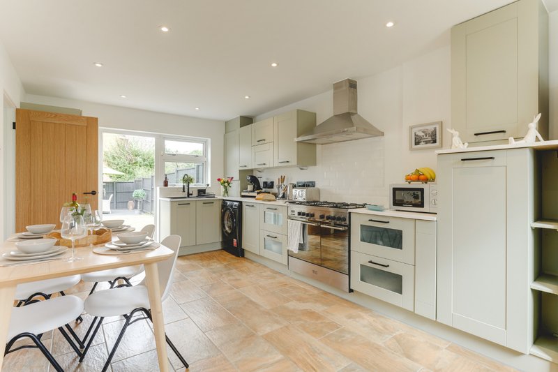 Modern kitchen and dining area with white cabinetry, wooden dining table, and garden doors
