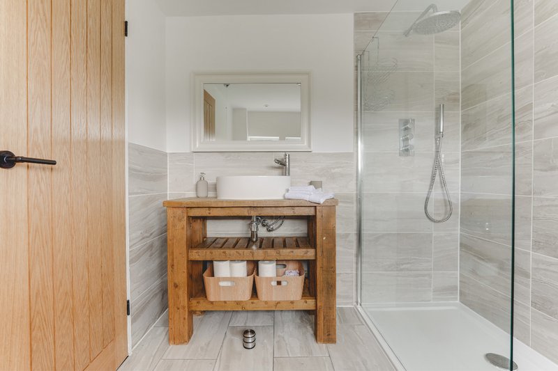Modern bathroom with wooden vanity, white subway tile, glass shower enclosure and mirror