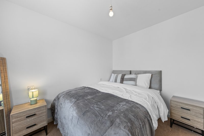 Bedroom with double bed, grey headboard, wooden nightstands and pendant light