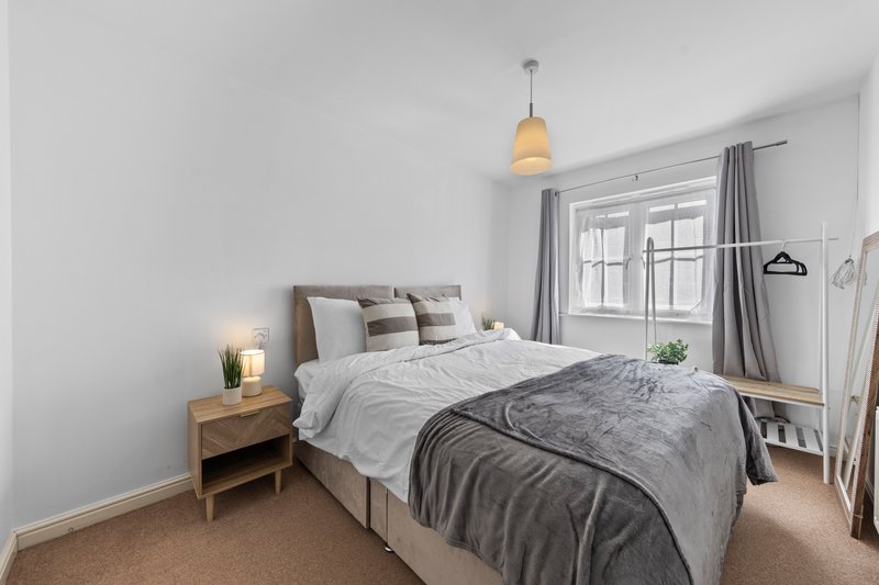 Bright bedroom with double bed, wooden nightstand, pendant light and large window