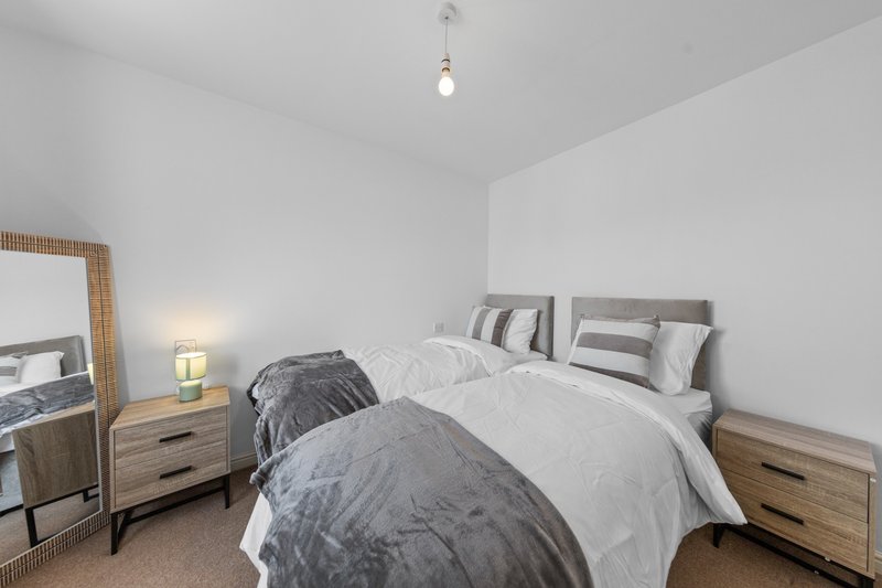 Modern bedroom with double bed, wooden nightstands, mirror, and pendant light fixture