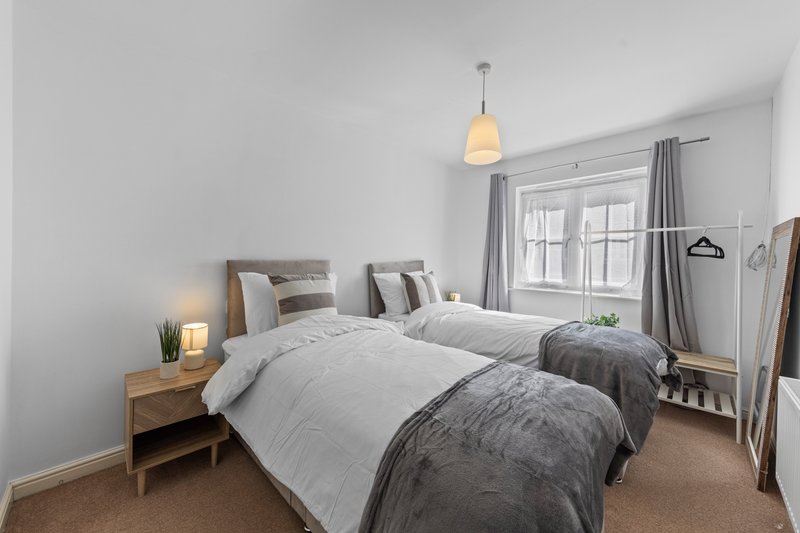 Bright modern bedroom with two single beds, wooden nightstand, pendant lamp and large window