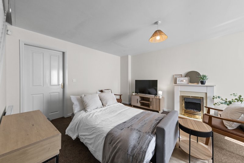 Bright bedroom with double bed, wooden furniture, electric fireplace and pendant light