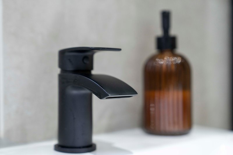 Modern bathroom sink with black faucet and amber glass soap dispenser bottle