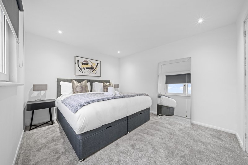 Modern bedroom with double bed, bedside tables, framed wall art, and grey carpet flooring