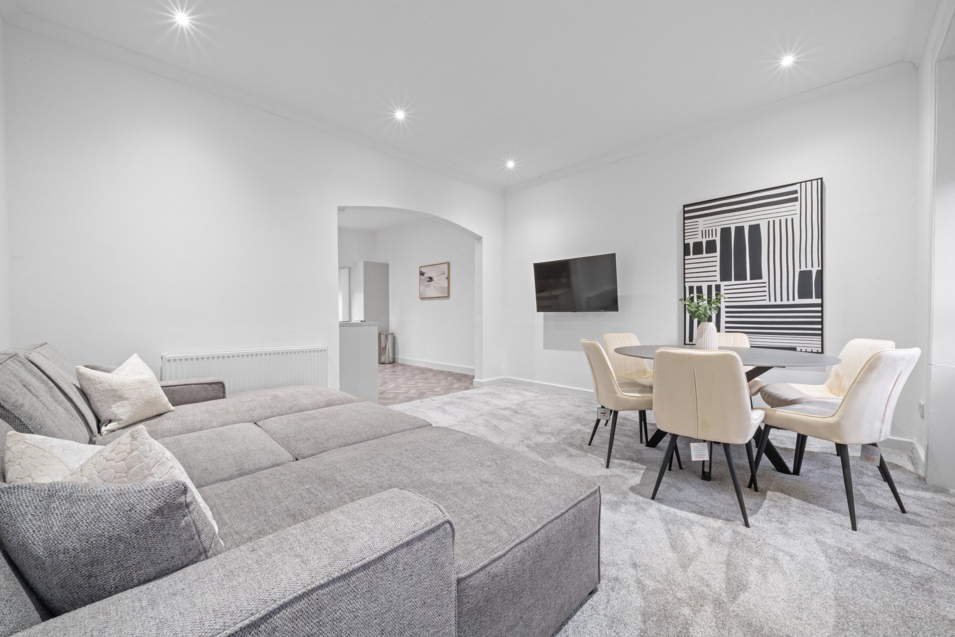 Modern living room with grey sectional sofa, dining table, chairs and wall art