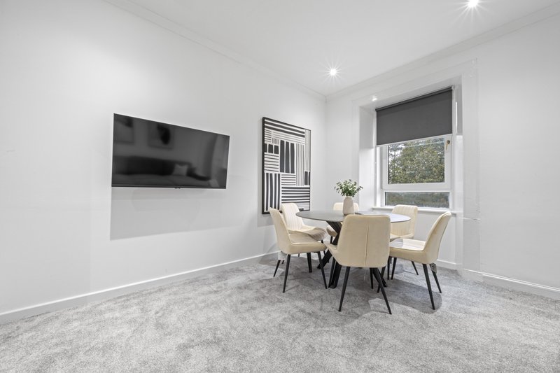Modern dining room with round table, four chairs, wall-mounted TV and window