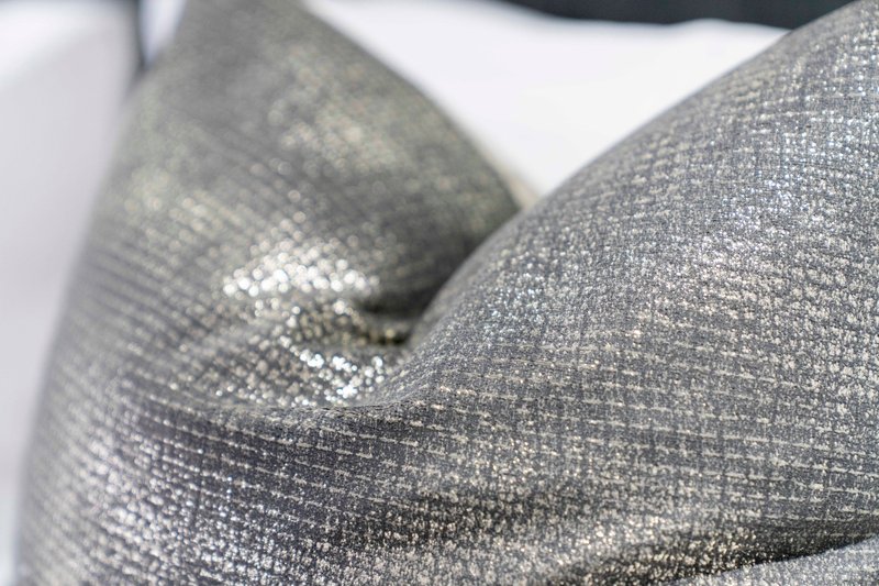 Close-up of grey and silver upholstered cushions and throws on furniture