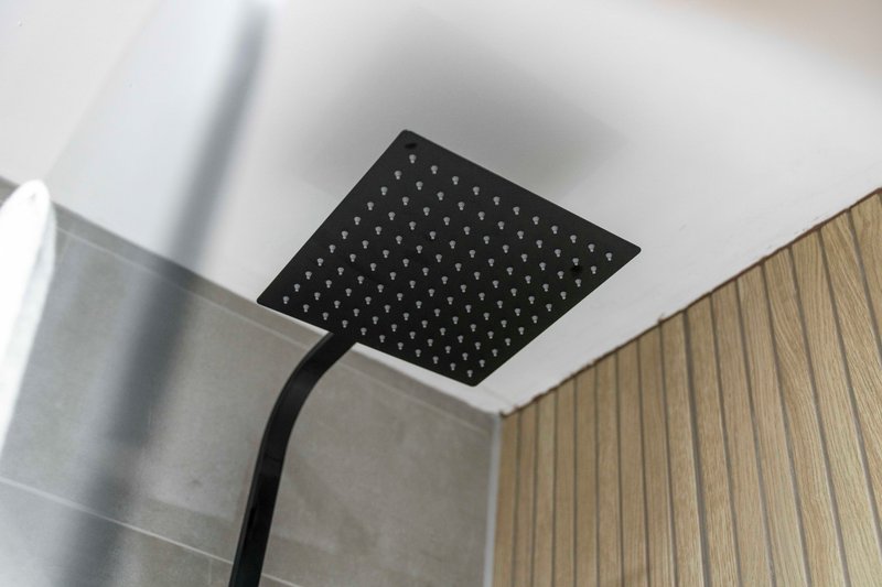 Modern bathroom ceiling with black rainfall showerhead and white surround