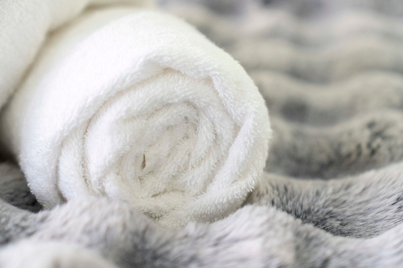 Rolled white towel on gray and white striped fabric surface