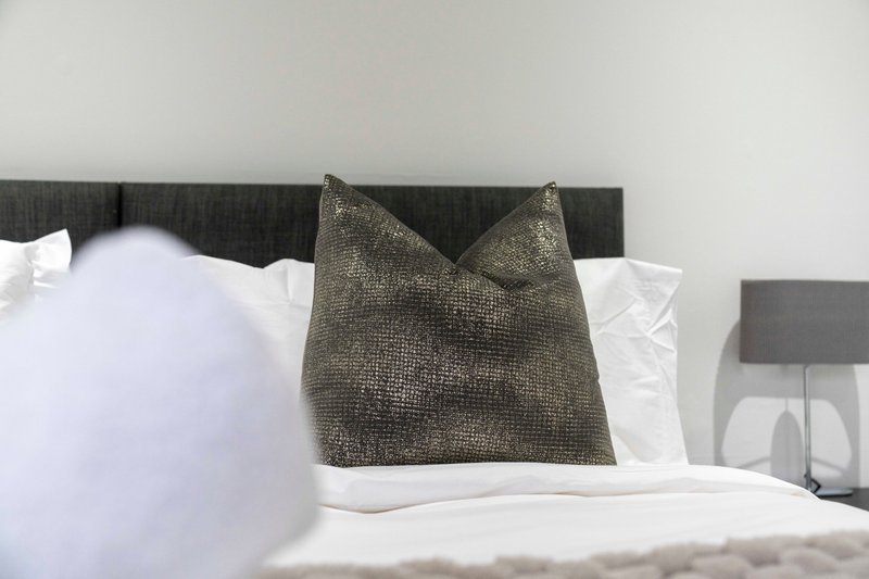 Bedroom with upholstered headboard, white bedding, and decorative cushions