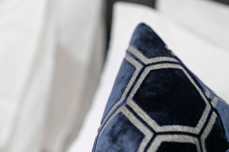 Close-up of decorative blue cushion with geometric pattern on bed