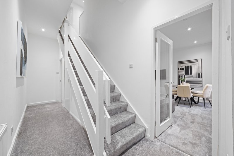 Modern staircase with white railings, grey carpet runner and recessed lighting