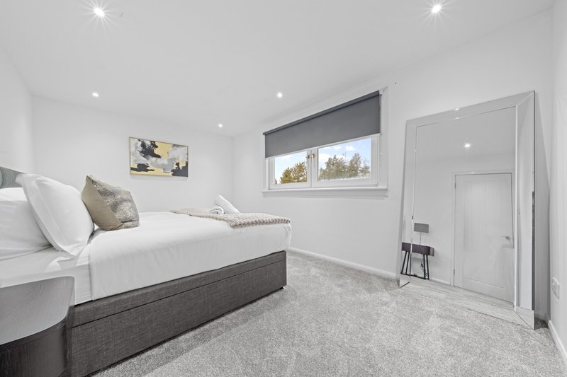 Modern bedroom with double bed, grey upholstered frame, white bedding and window
