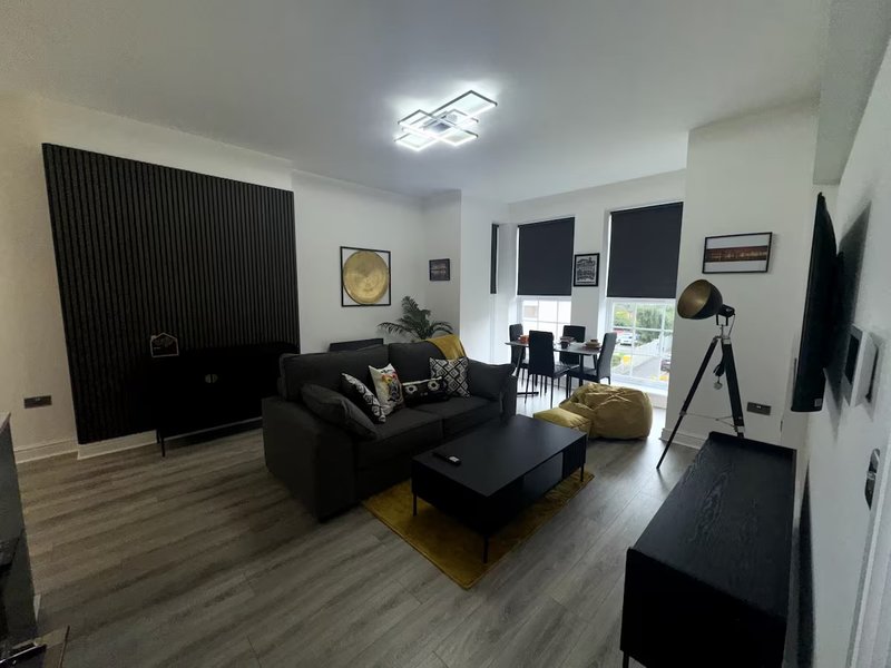 Modern living room with black sofa, coffee table, large TV, and contemporary decor