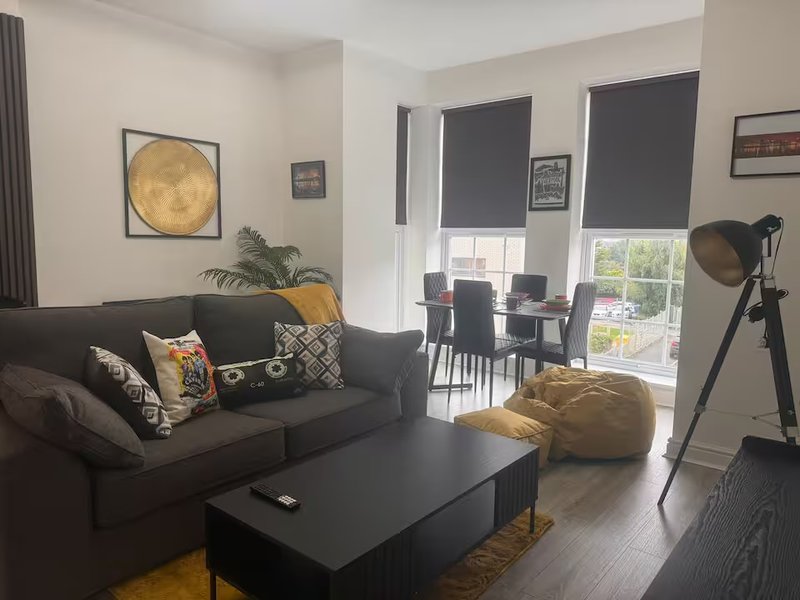 Modern living room with dark sofa, black coffee table, decorative cushions and moon wall art