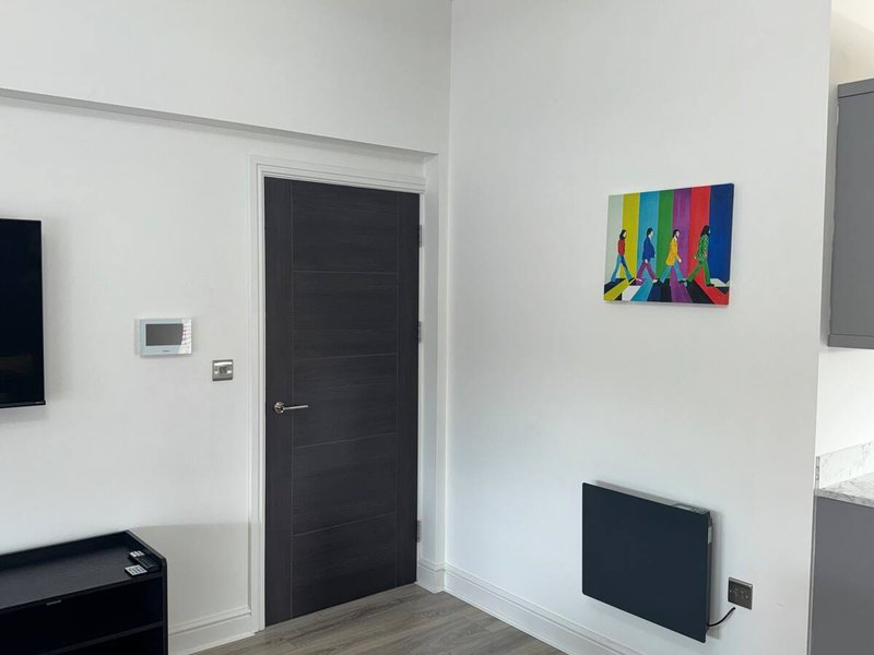 Modern living room with white walls, black door, colorful pop art canvas, and dark furnishings