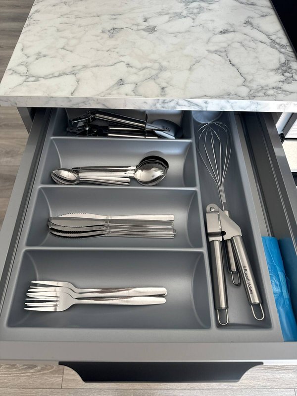 Kitchen drawer organizer with marble countertop, displaying cutlery and utensils