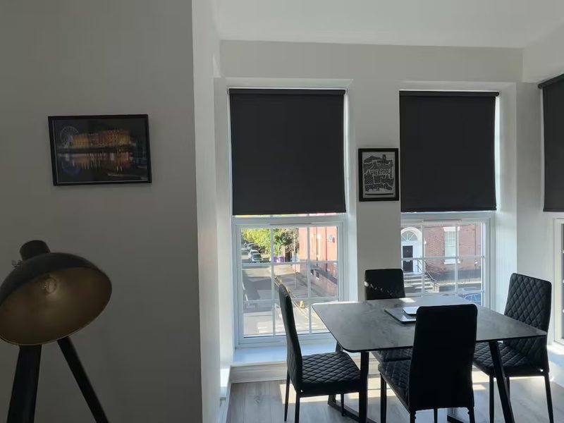 Modern dining area with black table, chairs, floor lamp and large windows with blinds