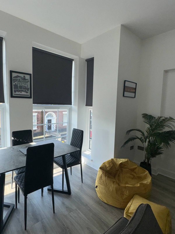 Modern open-plan office space with desk, black chairs, yellow bean bag and potted plant