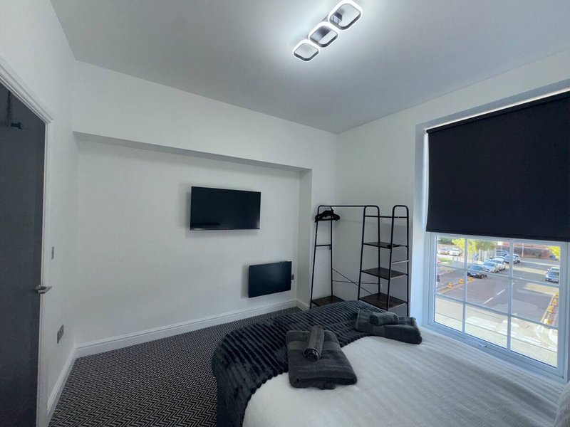 Modern bedroom with double bed, wall-mounted TV, shelving unit and large window with city view