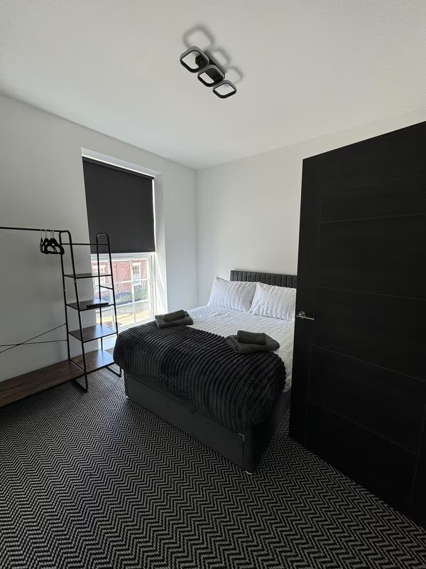Modern bedroom with twin beds, black wardrobe, geometric floor pattern and ceiling light