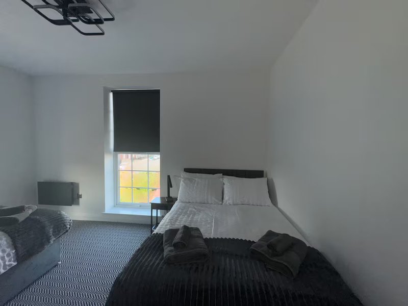 Bright bedroom with double bed, window with blind, and carpeted floor