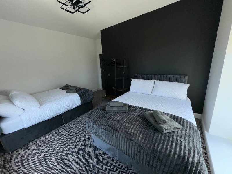 Modern bedroom with two single beds, black accent wall, and geometric patterned carpet